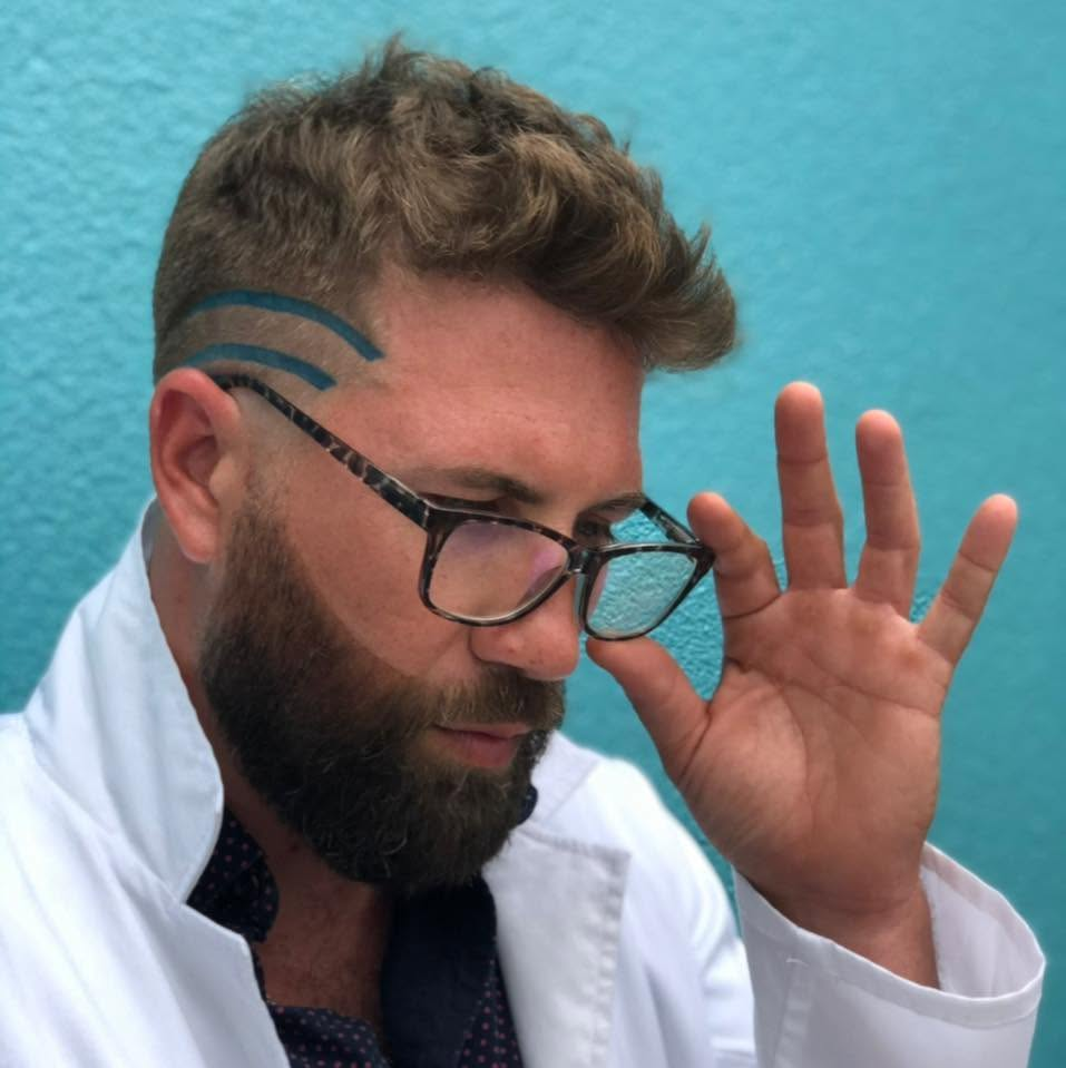 Nick 2 in glasses against a bright blue wall