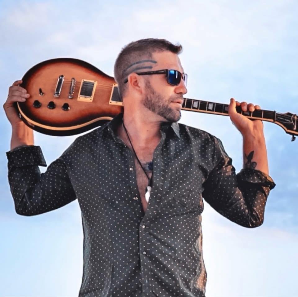 Nick 2 holding a guitar for a press photo
